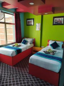 two beds in a room with green walls at Three Brothers Apartment and Hotel in Kathmandu
