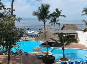 a large swimming pool with palm trees and the ocean at Villa Marina in Puerto Vallarta