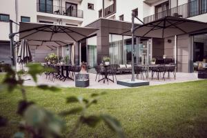 a patio with tables and chairs and umbrellas at ADEBAR Stadthotel in Dingolfing