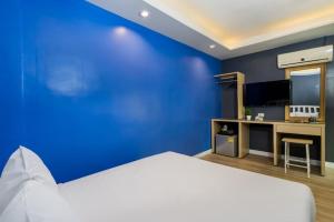 a blue room with a bed and a desk at Metro Link Ratchada Hotel in Bangkok