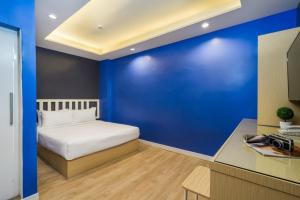 a blue bedroom with a bed and a blue wall at Metro Link Ratchada Hotel in Bangkok