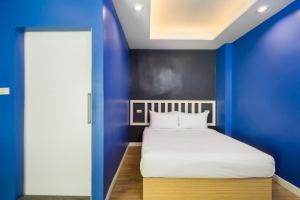a blue room with a bed and a blue wall at Metro Link Ratchada Hotel in Bangkok
