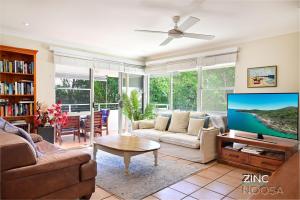a living room with a couch and a tv at Yaringa Apartment 1 - Moments from Noosa Main Beach in Noosa Heads