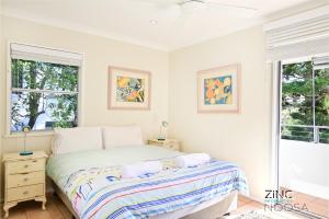a white bedroom with a bed and two windows at Yaringa Apartment 1 - Moments from Noosa Main Beach in Noosa Heads
