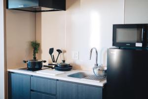 a kitchen with two pots and a sink and a refrigerator at MIMARU SUITES KYOTO CENTRAL in Kyoto