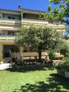 a large building with a tree in front of it at Apartments Kaja in Rab