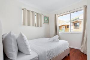 a white bedroom with a bed and a window at Winston Waves in Bongaree