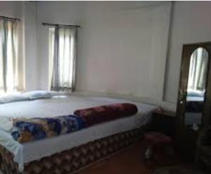 a bedroom with a large bed with two windows at Akarshan Bono Bunglow in Lataguri