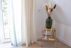 eine Vase mit Blumen auf einem Tisch neben einem Fenster in der Unterkunft NOVA - See APT 22 I Phantasialand I Cologne I Bonn in Erftstadt