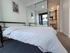 - une chambre avec un grand lit blanc et un grand miroir dans l'établissement Swanston Central 17, à Melbourne