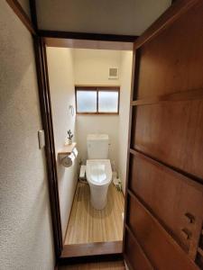 a bathroom with a toilet and a wooden door at 天然温泉付き / 川の音を聞き過ごす昭和民家 in Atami