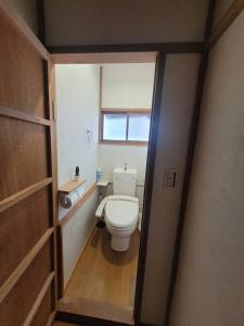 a small bathroom with a toilet and a window at 天然温泉付き / 川の音を聞き過ごす昭和民家 in Atami