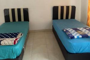 two beds sitting next to each other in a room at OYO 93100 Harapan Homestay Syariah in Parit