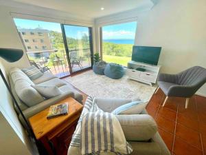 a living room with a couch and a television at 'Serenity Now' Shoal Bay Beach Front with All Linen, WiFi and Air Con in Nelson Bay