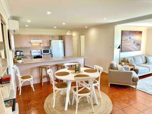 a kitchen and a living room with a table and chairs at 'Serenity Now' Shoal Bay Beach Front with All Linen, WiFi and Air Con in Nelson Bay