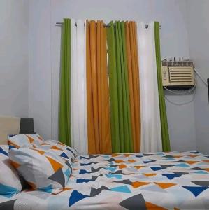 - une chambre dotée d'un lit avec des draps et des rideaux colorés dans l'établissement Unique apartment, à Nsukka