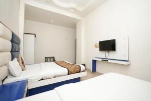 um quarto de hotel com duas camas e uma televisão em Hotel Sai Dham International em Nova Deli