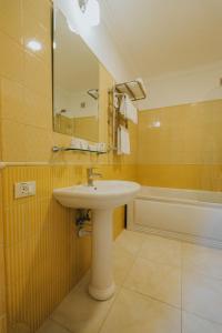 y baño con lavabo, espejo y bañera. en Premier Geneva Hotel, en Odessa