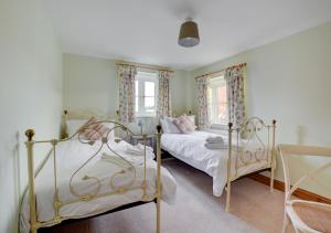 a bedroom with two beds and two windows at Finder's Cottage in Docking