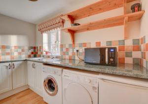 a kitchen with a washing machine and a microwave at Finder's Cottage in Docking
