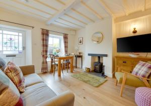 sala de estar con sofá, TV y mesa en Munton Cottage en Crakehall