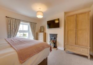 a bedroom with a bed and a dresser and a window at Munton Cottage in Crakehall