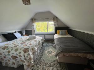 sypialnia na poddaszu z 2 łóżkami i oknem w obiekcie PINEBROOK BnB 1st Floor Apartment shared bathroom budget w mieście Killybegs