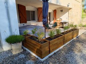 a patio with four wooden planters with plants in it at Écrin de nature sous les pins in Aurons