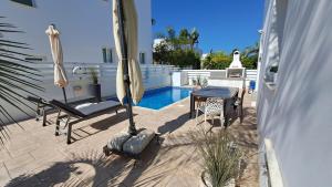 a patio with a table and an umbrella and a pool at Relaxing Avra Villa with Private Pool & Garden Near Protaras in Paralimni