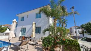 a house with a palm tree and a swimming pool at Relaxing Avra Villa with Private Pool & Garden Near Protaras in Paralimni