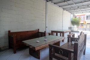 a patio with wooden tables and benches and a wall at RedDoorz Syariah near Pakuwon Mall Jogja in Kejayan +32 photos