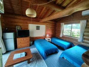 a room with two beds in a log cabin at Pension Shishikui in Shishikui