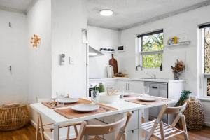 a white kitchen with a table and chairs at Ray's Place by the Riverside in Glenelg