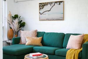 a green couch in a living room with a table at Ray's Place by the Riverside in Glenelg
