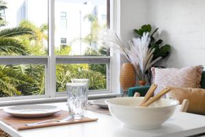 a table with plates and bowls on a table with windows at Ray's Place by the Riverside in Glenelg