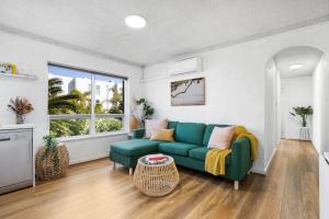 a living room with a green couch and a window at Ray's Place by the Riverside in Glenelg +10 photos