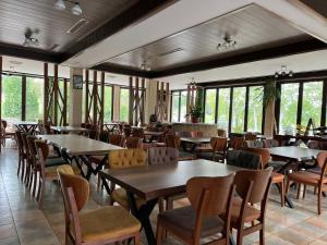 uma sala de jantar com mesas, cadeiras e janelas em Ваканционно селище Романтика em Kirkovo
