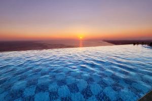 a infinity pool with the sunset in the background at Gangneung Chonpines Ocean Suites Hotel in Gangneung