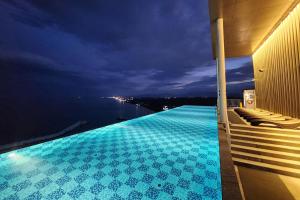 a swimming pool with a view of the water at night at Gangneung Chonpines Ocean Suites Hotel in Gangneung