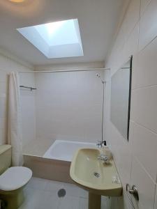 a bathroom with a sink and a toilet and a skylight at Dúplex 8, en primera línea de playa in Sanlúcar de Barrameda