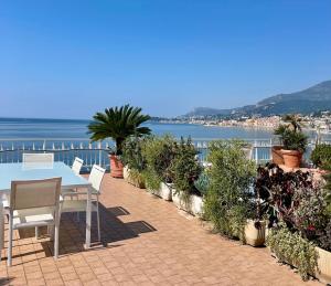 eine Terrasse mit einem Tisch, Stühlen und Meerblick in der Unterkunft Una terrazza sul mare - Balzi Rossi in Ventimiglia