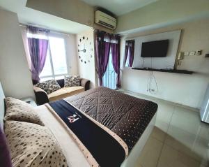 een kamer met een bed, een bank en een tv bij Apartemen grand dhika city by PLANET ZONA in Padurenan
