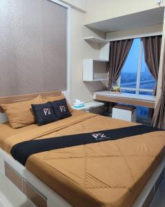 een slaapkamer met een groot bed en een raam bij Apartemen grand dhika city by PLANET ZONA in Padurenan