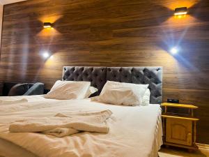 a bedroom with a white bed with a wooden wall at Panorama View-Stoykite in Stoykite