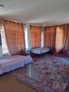 a bedroom with two beds and curtains and a rug at private room with cultural experience and great landscapes in Şirfah