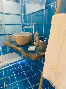 ein blau gefliestes Bad mit einem Waschbecken und einer Badewanne in der Unterkunft Da Ida in Bosa