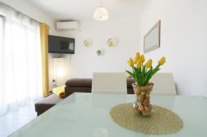 una sala de estar con una mesa con un jarrón de flores en Apartman Paštura, en Vodnjan
