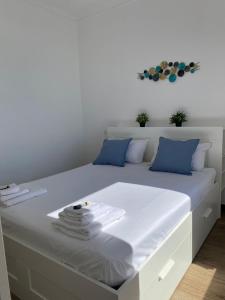 Una cama blanca con almohadas azules y toallas. en La finestrella sul porto, en Génova
