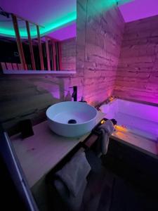een badkamer met een wastafel en een bad met paarse verlichting bij Zen Room in LʼIsle-sur-le-Doubs