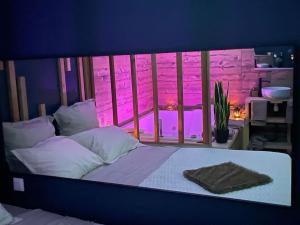een slaapkamer met een bed en een raam met roze verlichting bij Zen Room in LʼIsle-sur-le-Doubs